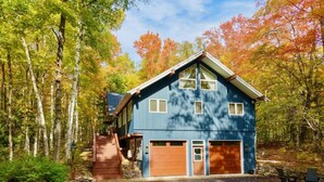 Ein zweistöckiges Haus mit Garage, umgeben von einem Wald im Herbstlaub.