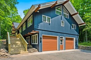 A two-story house with a wooden staircase, a garage, and a stone wall.