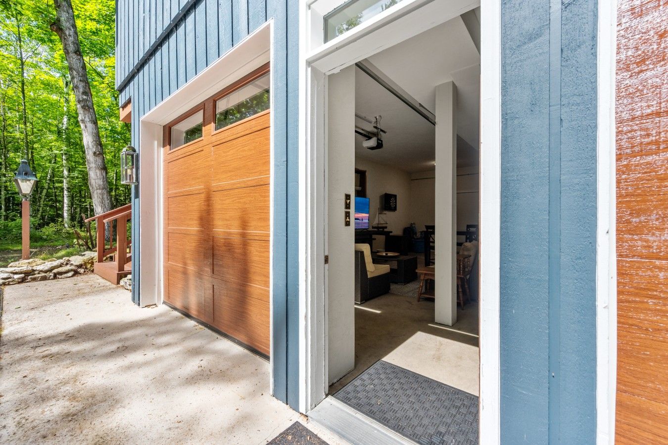 A modern house with a garage door, a living room with a TV, and a dining area.