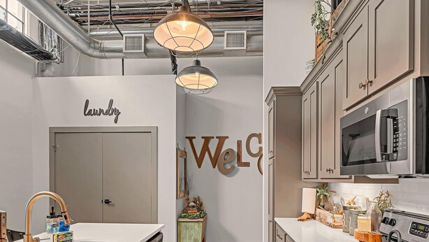 A modern kitchen with a central island, stainless steel appliances, and pendant lighting. - Waco Memory Lane, Downtown Luxury Loft- Steps to Silos/Baylor/McLane (Waco)
