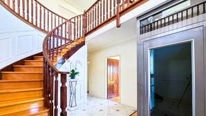 A wooden staircase with a glass elevator door. - Classic Hampton Retreat (Hampton)