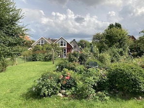 Um bairro residencial com casas, gramado e um jardim com diversas plantas e flores.