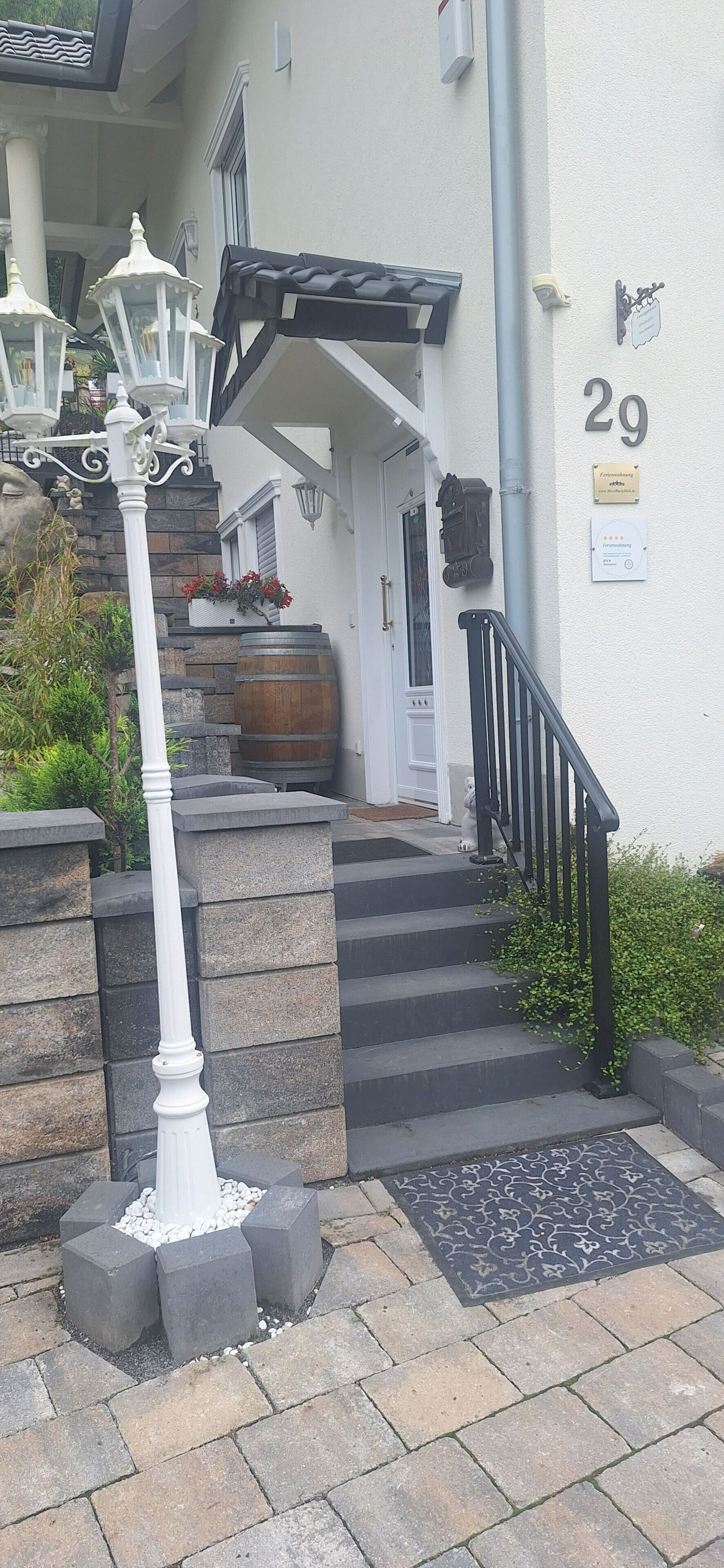 Une entrée d’immeuble avec un escalier, un lampadaire blanc et une plaque portant le numéro « 29 ».