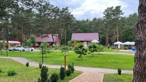 A residential area with a paved pathway, small trees, and a red-roofed building. - Holiday Home 'Eichelhäher' with Private Terrace, Private Garden and Wi-Fi (Zossen)