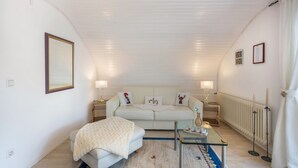 A bedroom with a bed, a glass table, a white sofa, and a radiator.