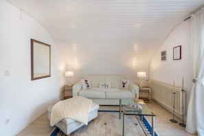A bedroom with a bed, a glass table, a white sofa, and a radiator.