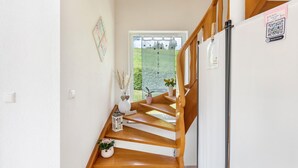 A staircase leading to a balcony with a view of greenery, a refrigerator, and a QR code on the wall.