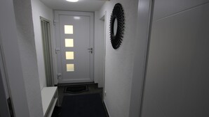 A narrow hallway with a door at the end, a welcome mat, and a decorative wreath on the wall. - Apartment 'Ferienwohnung Am Bärenstein' with Balcony and Wi-Fi (Bärenstein)