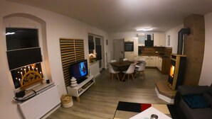 A living room with a TV, dining area, and kitchen. - Apartment 'Ferienwohnung Am Bärenstein' with Balcony and Wi-Fi (Bärenstein)