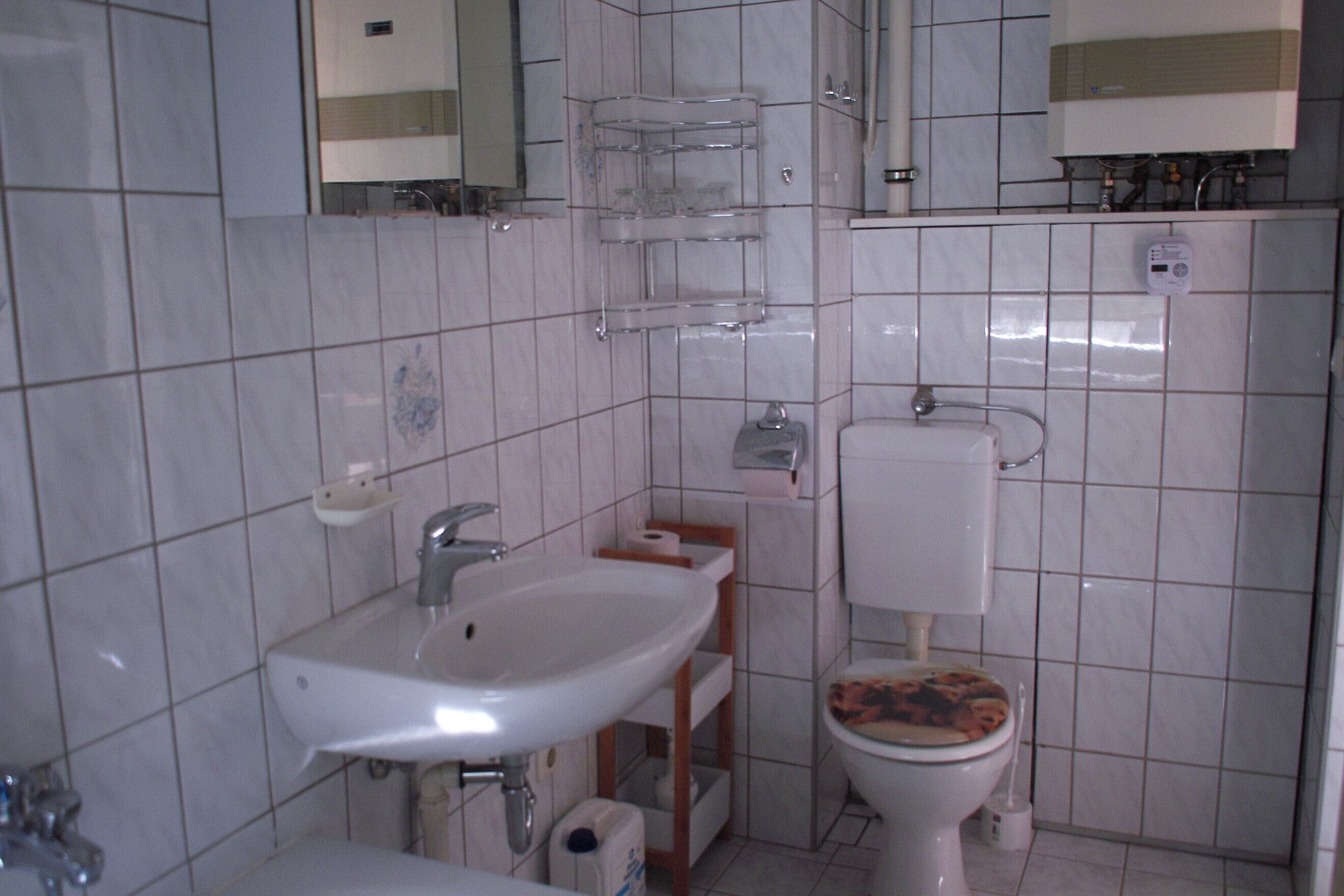 A bathroom with a white sink, toilet, and a mirror above the sink.