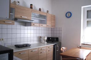 Una cocina con armarios de madera, cafetera, balanza y un reloj en la pared.