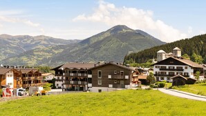 A mountain village with traditional wooden buildings, a paved road, and a mountain in the background. - Holiday Apartment "Nr 2 Haus Voglreiter" with Mountain View, Shared Garden & Wi-Fi (Kaprun)