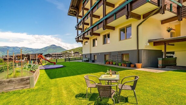 A hotel with a well-maintained lawn, outdoor seating, and mountain views. - Holiday Apartment "Nr 2 Haus Voglreiter" with Mountain View, Shared Garden & Wi-Fi (Kaprun)