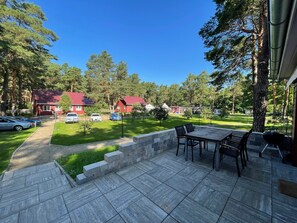 En terrasse med et bord og stole, grill og en stenvæg.