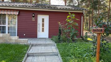 A red building with a white door, a small garden, and a sign that reads 'Specht'.