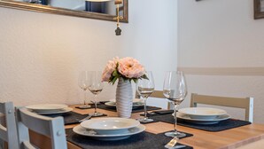 A dining table set with plates, glasses, and a vase of flowers.