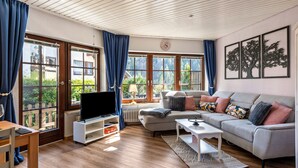A living room with a sofa, TV, and windows.