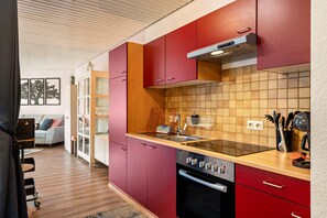 Une cuisine moderne avec des meubles rouges, une cuisinière noire et un dosseret carrelé.