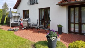 Una casa con un patio, mobiliario exterior y una parrilla.