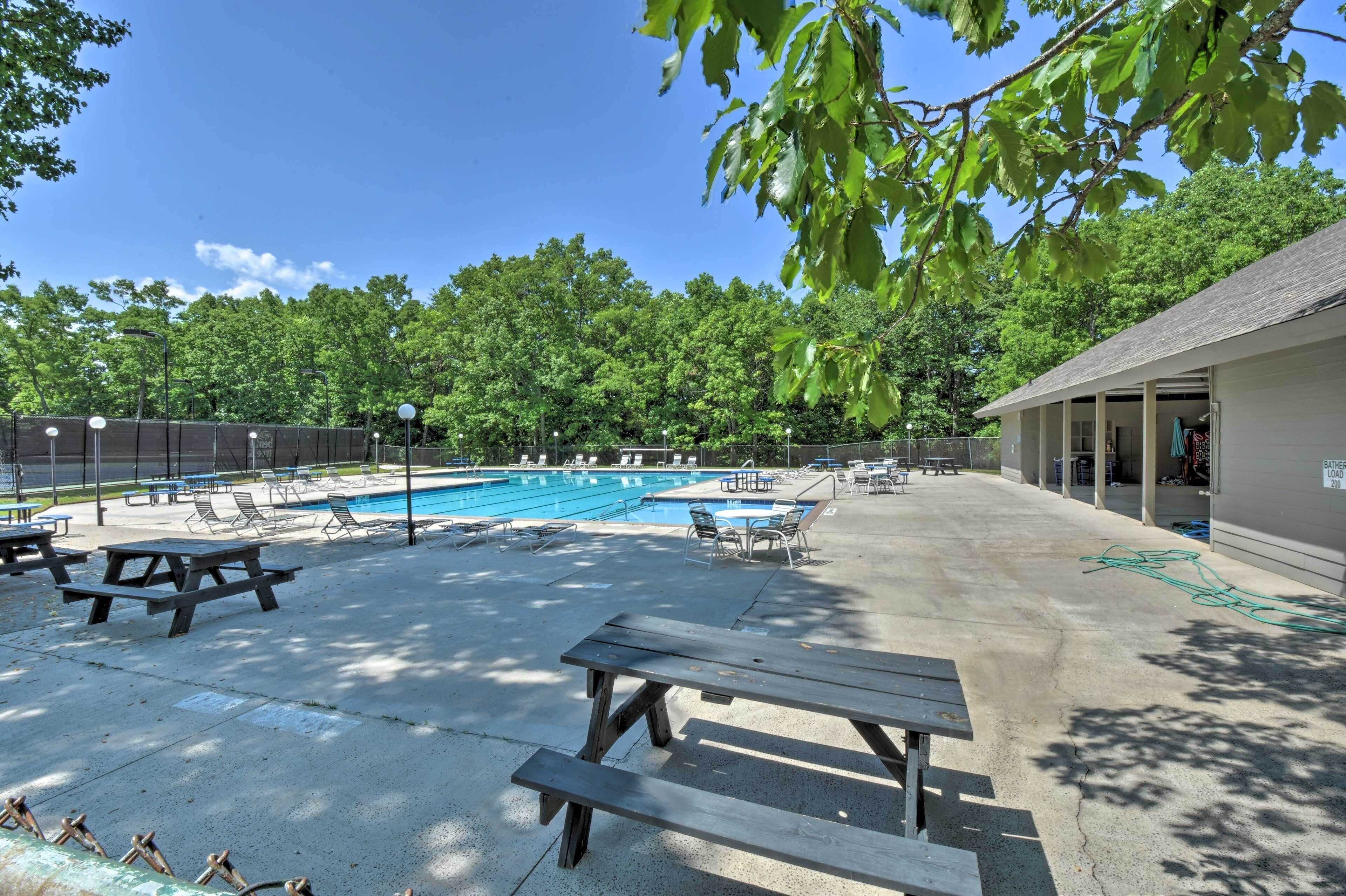 Un espace piscine avec des chaises longues et des tables de pique-nique.