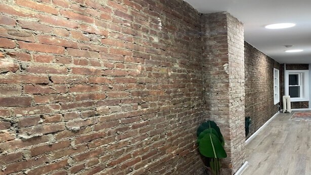 A hallway with exposed brick walls and a wooden floor. - Brick City Dreams  A minute away from The Prudential Center! 4 mins from NJ PAC! (Newark)