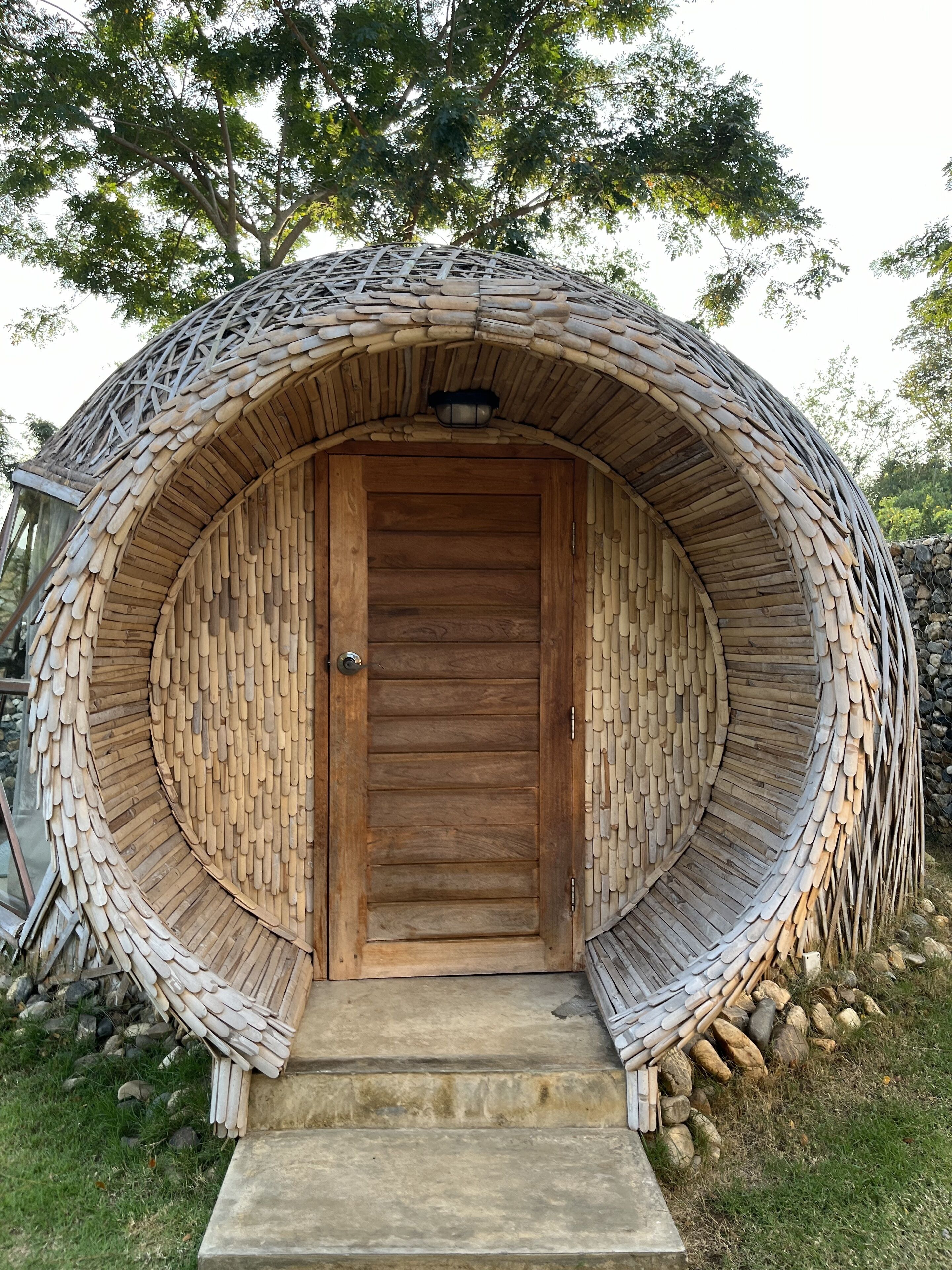 Una estructura circular con una puerta de madera y escalones que la conducen.