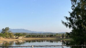 Un área de spa con bañera de hidromasaje, terraza de madera y vistas a un lago y montañas.