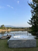 A spa area with a hot tub, wooden deck, and a view of a lake and mountains.