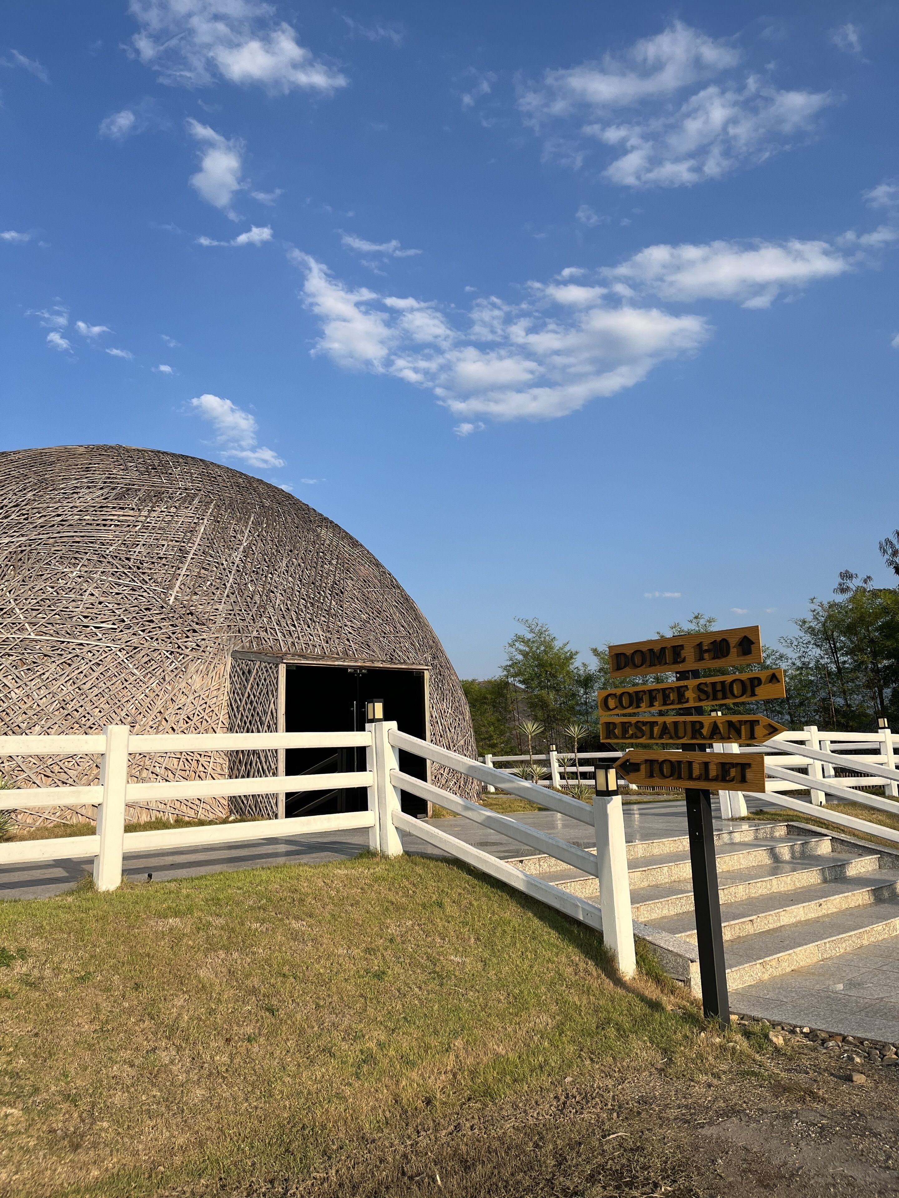 A dome-shaped building with a wooden signpost indicating directions to the Dome, Coffee Shop, Restaurant, and Toilet.