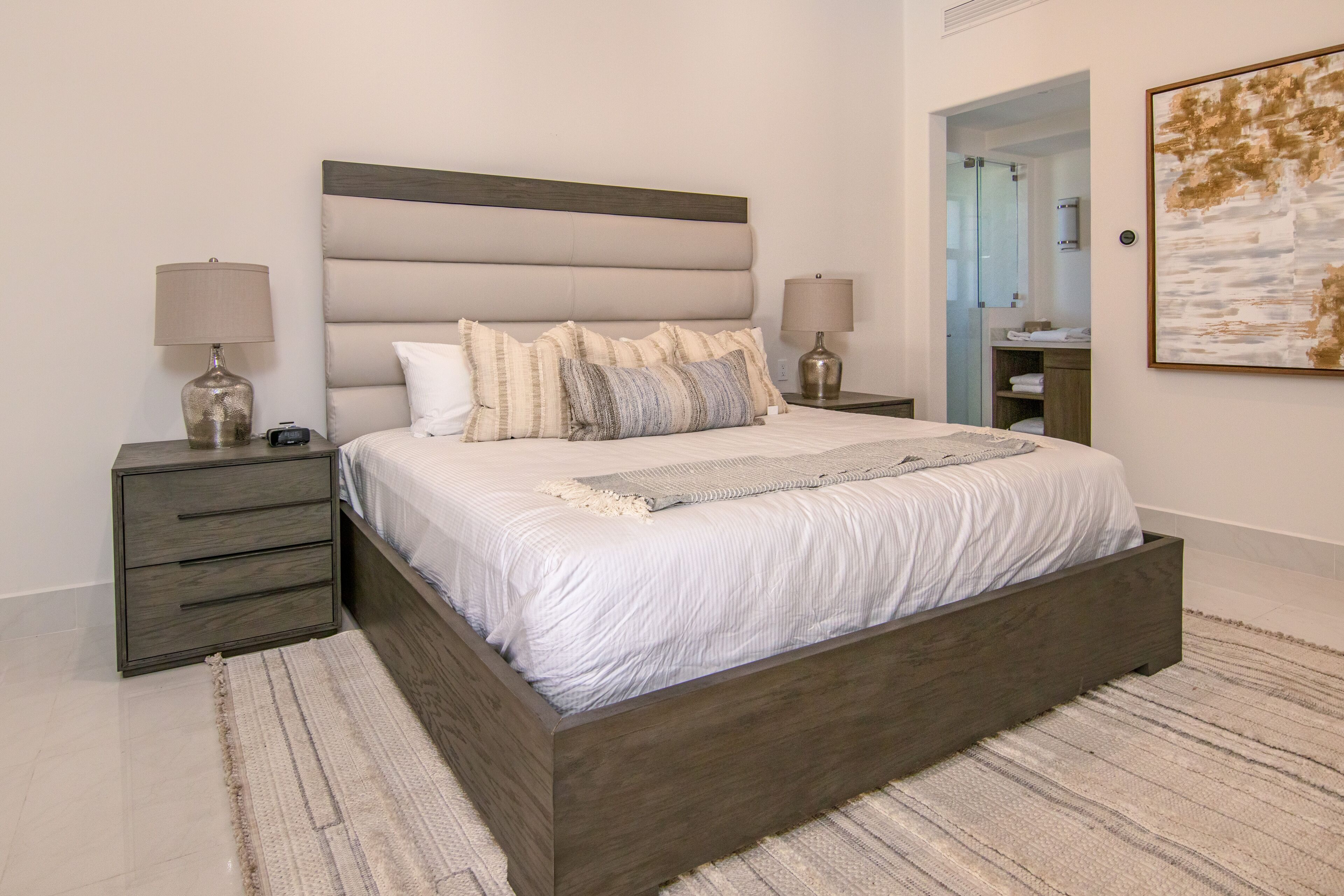 Une chambre moderne avec un grand lit, deux tables de chevet et une commode.