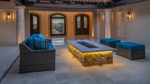 An outdoor seating area with wicker furniture and a stone fire feature.