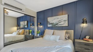 A modern bedroom with a large bed, a mirror, bedside tables, and a wall-mounted artwork. - Park Place (Colorado Springs)