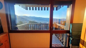 A room with a large window overlooking a mountainous landscape. - Studio Font-romeu Vue Imprenable Plein sud sur le Cambre D'aze ! (Font-Romeu-Odeillo-Via)