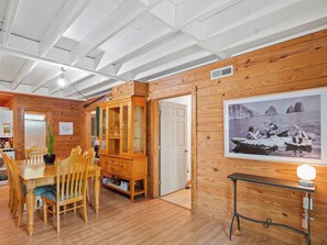 Ett rum med träpanel på väggarna, ett matbord, stolar, ett skåp och ett inramat fotografi på väggen.