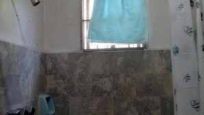A bathroom with a shower, a window with a blue curtain, and a tiled wall. - CVNB guesthouse (San Juan)