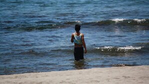 A person standing in shallow water near a sandy beach. - CVNB guesthouse (San Juan)