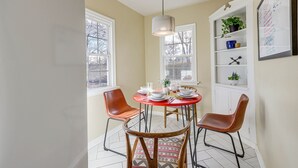 A dining area with a round table, two chairs, a hanging light fixture, and a whiteboard with writing on the wall. - Central Rapid City Home w/ Sunroom & Fireplace! (Rapid City)