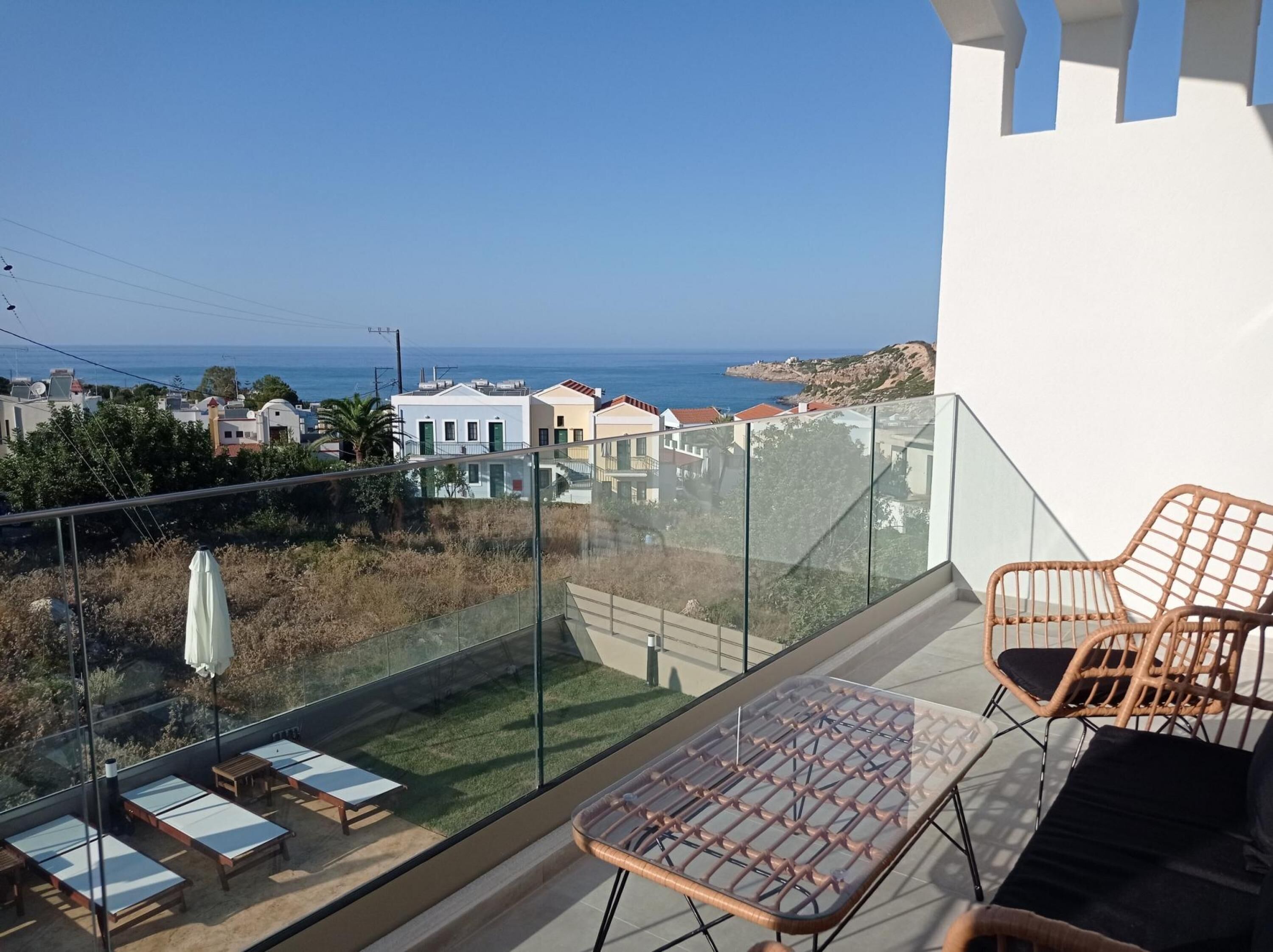 A balcony with glass railings, a wicker chair, and a table.