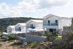 A modern villa with a pool, outdoor seating, and a view of the surrounding landscape.