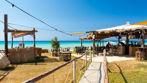 A beachside restaurant with outdoor seating, a wooden deck, and a view of the ocean. - Villa Erato in Nea Dimmata (Nea Dimmata)