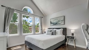 Une chambre moderne avec un grand lit, une table de chevet, une chaise et une fenêtre avec des rideaux.