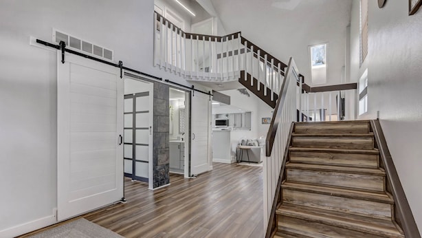 Un intérieur spacieux avec un escalier en bois, une porte coulissante et un coin cuisine.