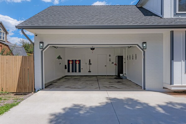 A garage with a white exterior, a concrete driveway, and a wooden fence in the background.