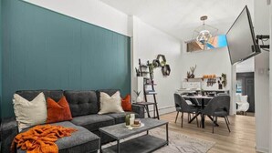 A modern living room with a dark grey sofa, a coffee table, and a dining area with a white table and chairs.