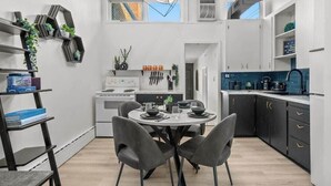 A modern kitchen with a dining area, featuring a round table, dark chairs, and a built-in stove.