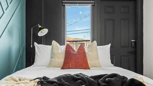 A bedroom with a bed, a lamp, and a view through a door.
