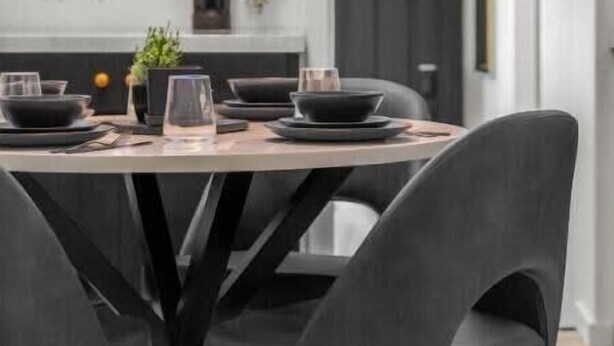 A modern dining area with a round table set for four, featuring black chairs and a minimalist design.