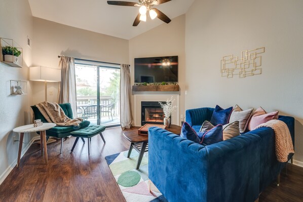 A modern living room with a blue sofa, a fireplace, and a TV mounted on the wall. - Branson Family-Friendly Condo w/ Golf Package! (Branson)