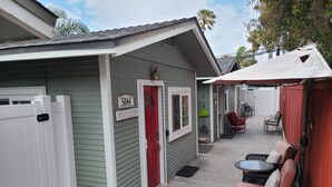 A small, single-story building with a red door and a sign reading "5044 Beach House." - Waypoint Cottage, one block from the beach! (San Diego)
