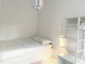 A minimalist bedroom with a bed, a white wardrobe, and a ceiling light fixture. - Wit II, Near Metro, Train N7670 (Brussels)